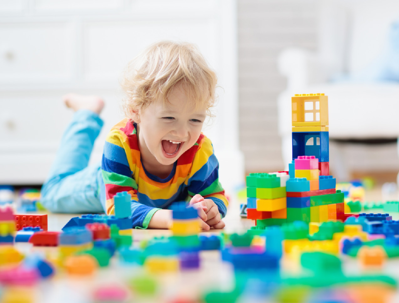 Toddler laughing while playing with brightly colored blocks.