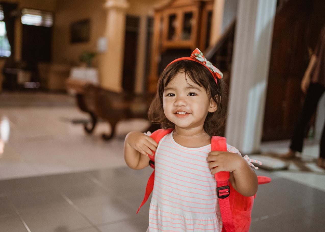 Little girl with red back pack ready for school.